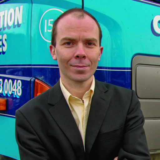 a man in a suit jacket and tie standing in front of a turquoise truck